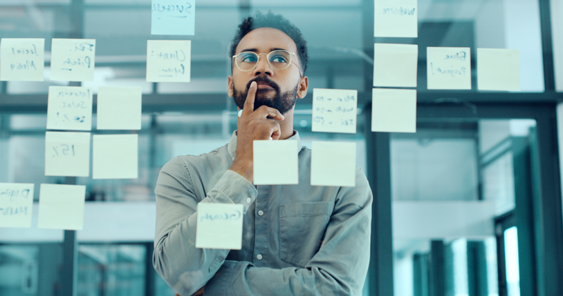 Man looking at sticky notes and thinking.