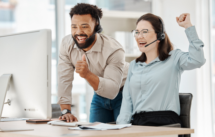 Customer support workers smiling at a computer.