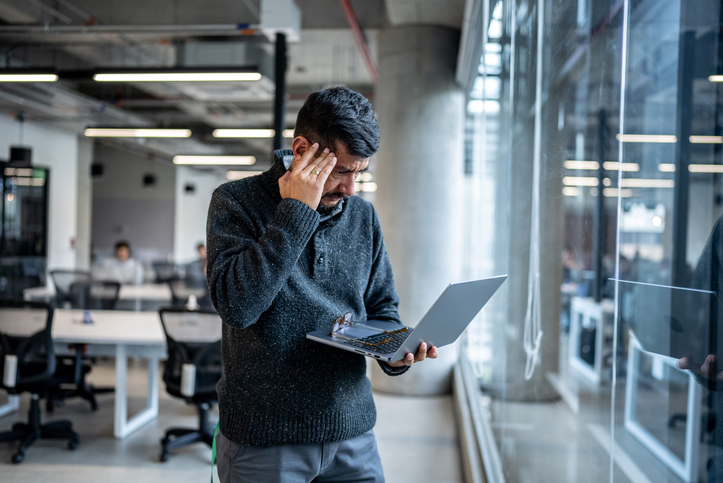 Worried mature man using laptop working at office.